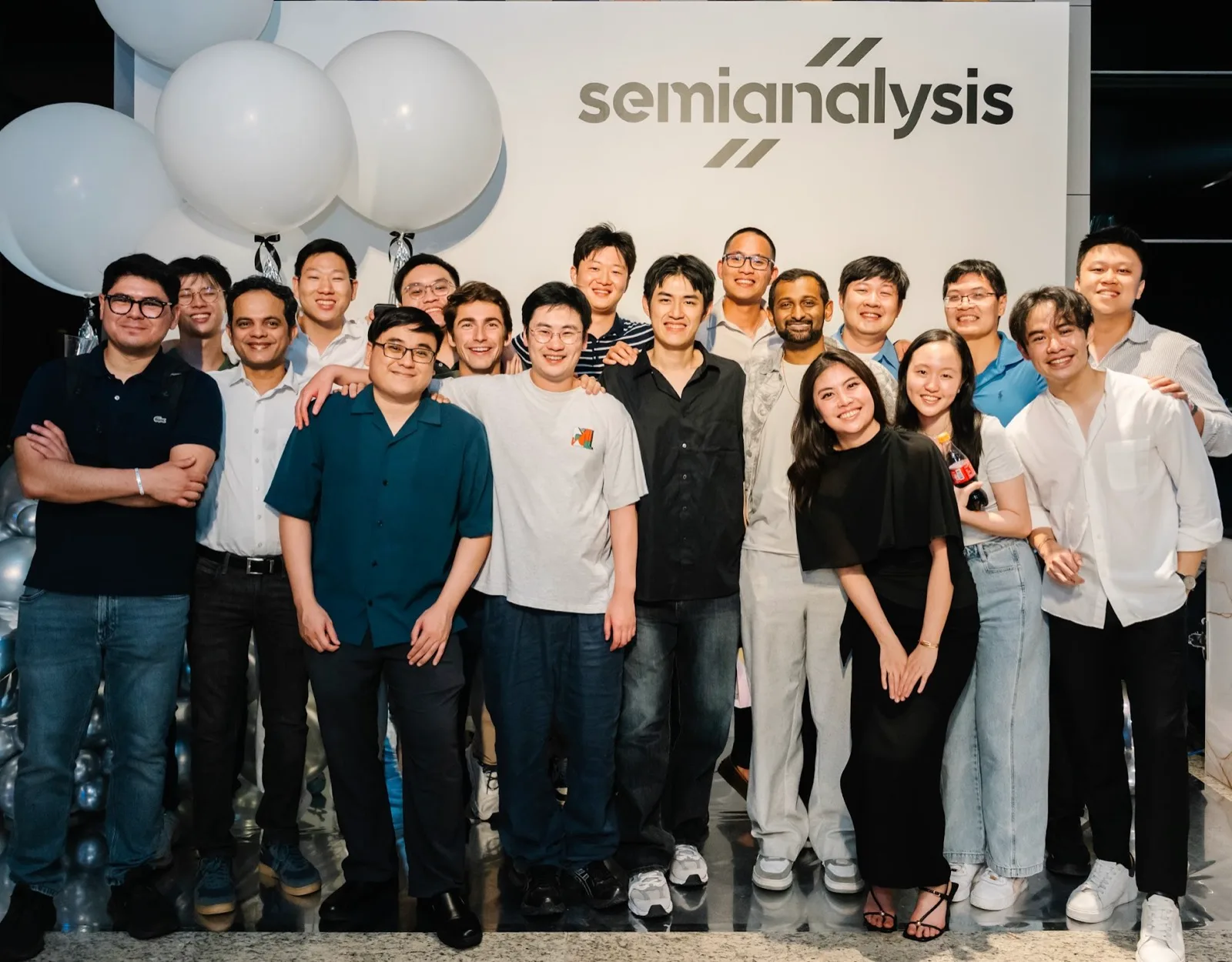 The SemiAnalysis team in front of a SemiAnalysis backdrop with white balloons at a company event